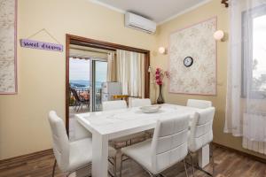 a dining room with a white table and white chairs at Camelia & Martina apartments in Opatija