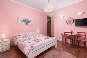 オパティヤにあるCamelia & Martina apartmentsのピンクの壁のベッド1台、テーブルが備わるベッドルーム1室が備わります。