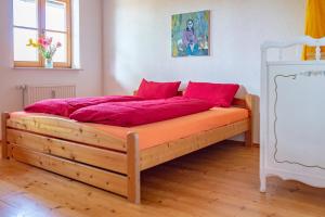 a bedroom with a wooden bed with red pillows at Ferienwohnung Kapellenhof in Herdwangen-Schönach
