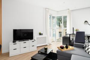 a living room with a couch and a flat screen tv at Cozy Black & White Studio in City Center with FREE GARAGE Poznań by Renters in Poznań