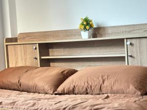 a bed with a wooden headboard with a plant on it at บ้านม่วนใจ๋สันกำแพง in San Kamphaeng