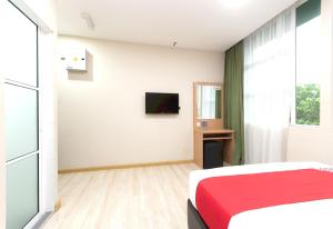 a bedroom with a red bed and a television at Capital O 89344 Labuan Avenue Hotel in Labuan