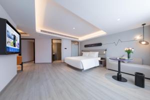 恵州市にあるAtour Light Hotel Huizhou Jinshanhu Ganghuiのベッド1台、薄型テレビが備わるホテルルームです。