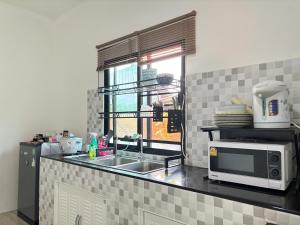 eine Küche mit einer Spüle und einer Mikrowelle in der Unterkunft บ้านม่วนใจ๋สันกำแพง in San Kamphaeng