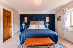 um quarto com uma cama grande e paredes azuis em Tree Tops House & Garden Cottage em Cheltenham