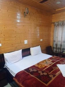 a bed in a room with a wooden wall at Pinez Guest House , Anantnag in Anantnāg