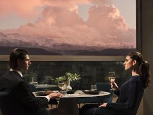 un hombre y una mujer sentados en una mesa con copas de vino en The Chania Hotel en La Canea