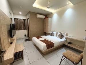 アーメダバードにあるHotel Kinaraのベッドとテレビが備わるホテルルームです。