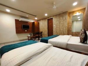 a hotel room with two beds and a television at Hotel Kinara in Ahmedabad