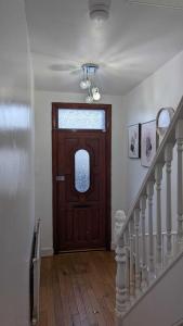 a hallway with a wooden door and a staircase at 3 bedroom house,4beds, 2 baths Ilford ,12 mins to Stratford in London