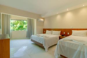 a hotel room with two beds and a window at Miola Hotel in Porto Seguro +28 photos