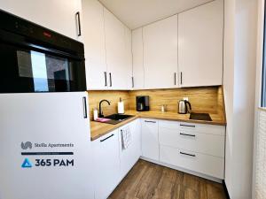 a kitchen with white cabinets and a black microwave at Apartament Różana Polana z Ogrodem - 365PAM in Sianozety