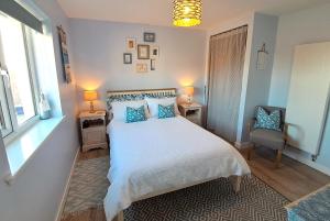 Un dormitorio con una cama blanca con almohadas azules y una silla en An Cois Na Mara Bed & Breakfast, en Laide