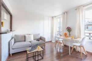 a living room with a couch and a table with a laptop at Comfortable flat - Montparnasse in Paris