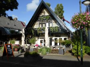 un bâtiment avec des fleurs et des plantes devant lui dans l'établissement Duinberk B&B hotel en Brasserie, à Schoorl