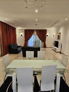 uma sala de estar com uma mesa de vidro e cadeiras em Octave's APT em Ponta Negra