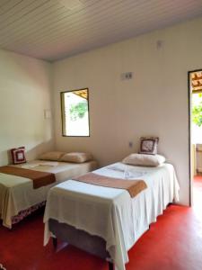 2 camas en una habitación con 2 ventanas en Chalé Ilha Verde-Cumuruxatiba, en Cumuruxatiba