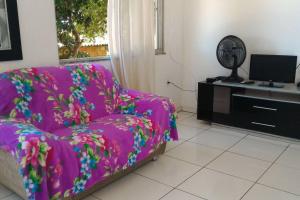 sala de estar con sofá rosa y TV en MARAVILHOSA CASA EM BÚZIOS AO LADO DO CENTRO en Búzios