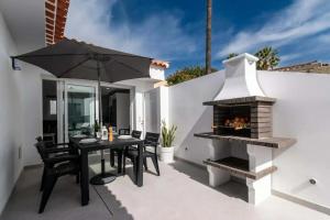 a patio with a table and an outdoor fireplace at Bungalow con piscina comunitaria in Chayofa