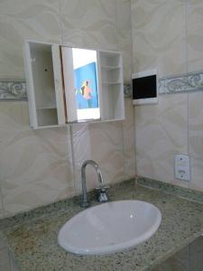 a sink in a bathroom with a mirror and a mirror at MARAVILHOSA CASA EM BÚZIOS AO LADO DO CENTRO in Búzios