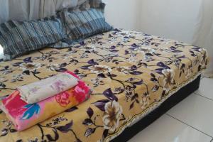 una cama con un patrón de flores y una almohada en MARAVILHOSA CASA EM BÚZIOS AO LADO DO CENTRO en Búzios