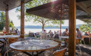 un grupo de mesas y sillas con personas sentadas en un restaurante en Hôtel L'Atelier de Donat, en Malbuisson