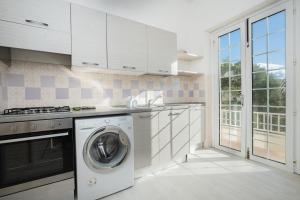 una cucina con lavatrice e asciugatrice accanto a una finestra di Tramontana vista mare 300m dalla spiaggia a Golfo Aranci