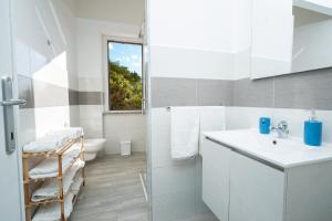 a white bathroom with a sink and a shower at "Tramontana" vista mare - 300m dalla spiaggia in Golfo Aranci +40 photos