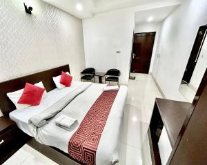 a bedroom with a large bed with red pillows at Hotel Siam International in New Delhi
