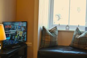 a living room with a couch and a television at The Old Surgery Crail- welcoming apartment in Crail