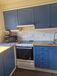 uma cozinha com armários azuis e um forno com placa de fogão em Madsgård em Etnesjøen
