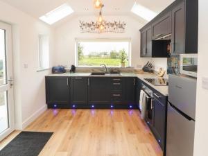 a kitchen with black cabinets and a wooden floor at Cherry Croft in Wigton