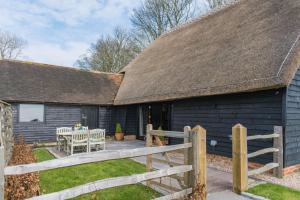 a black house with a wooden fence and a table at The Thatched Barn in Brabourne