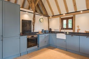 a large kitchen with blue cabinets and appliances at The Thatched Barn in Brabourne
