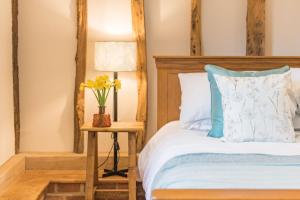 a bedroom with a bed and a table with a lamp at The Thatched Barn in Brabourne