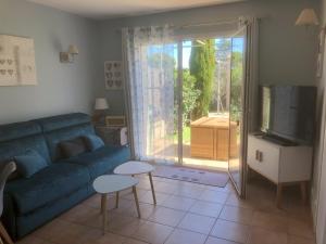 a living room with a blue couch and a sliding glass door at Le Mazet De Lélé in Saint-Rémy-de-Provence