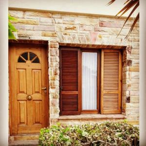a house with a wooden door and two windows at Departamento Peña in Carhué