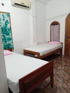 a room with two beds and a fan at Pearl Rest in Mannar