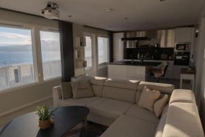 a living room with a white couch and a kitchen at Panorama view! Modern,Balcony/parking in Bodø