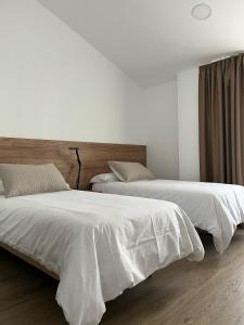 a bedroom with two beds with white sheets at Hostal Márquez in Yeste