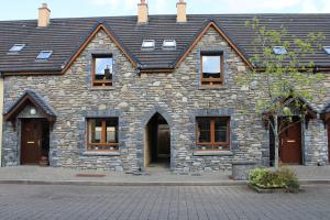 a stone building with windows and a roof at Cosy Holidayhomes Kenmare in Kenmare