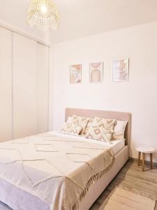 een witte slaapkamer met een bed en een kroonluchter bij Bed & Breakfast - Entre Paris & Disneyland in Roissy-en-Brie