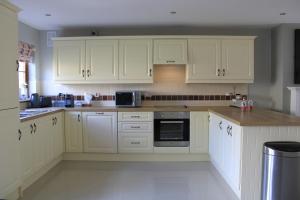 a kitchen with white cabinets and white appliances at Cosy Holidayhomes Kenmare in Kenmare