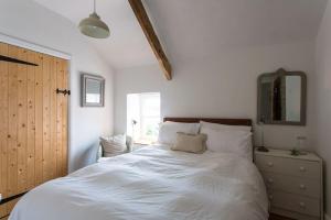 a bedroom with a white bed with a dresser and a mirror at Quay Cottage Llandeilo in Llandeilo