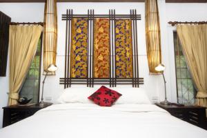 a bedroom with a white bed with a red pillow on it at The Green Palm in Haad Pleayleam