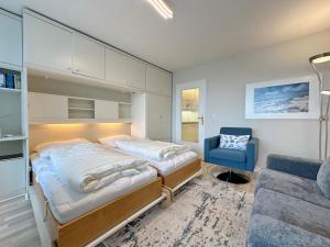 - une chambre avec deux lits et une chaise bleue dans l'établissement Metropol, Whg 92, Landseite, à Westerland