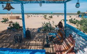 ダフラにあるSecret Spot Dakhlaの浜辺を眺めながら、ポーチに腰掛けている女性
