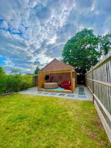 einen Hinterhof mit einem Schuppen mit einem Sofa und einem Zaun in der Unterkunft 1 Bedroom home with hot tub & private garden in Orpington