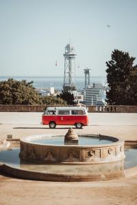 einem roten und weißen Van neben einem Brunnen in der Unterkunft Retro VW Kombi T2 Campervan in Hospitalet de Llobregat