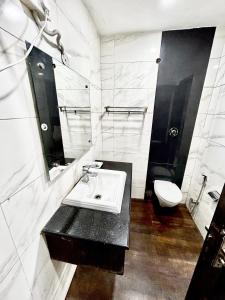 a white bathroom with a sink and a toilet at Hotel Siam International in New Delhi